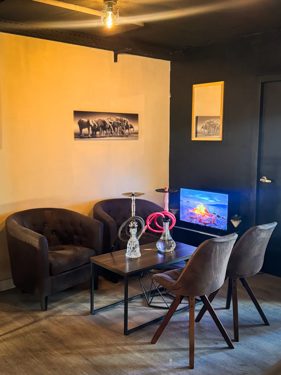 Un rincón con dos butacas, una mesa baja, sillas y una pantalla